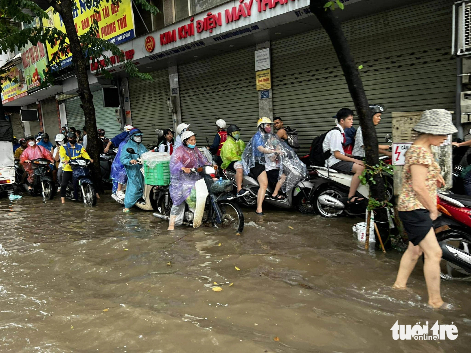 Motorcyclists and pedestrians opt to travel along the sidewalks on Nguyen Trai Street where the water is much shallower, Hanoi, September 16, 2024. Photo: Nam Tran / Tuoi Tre