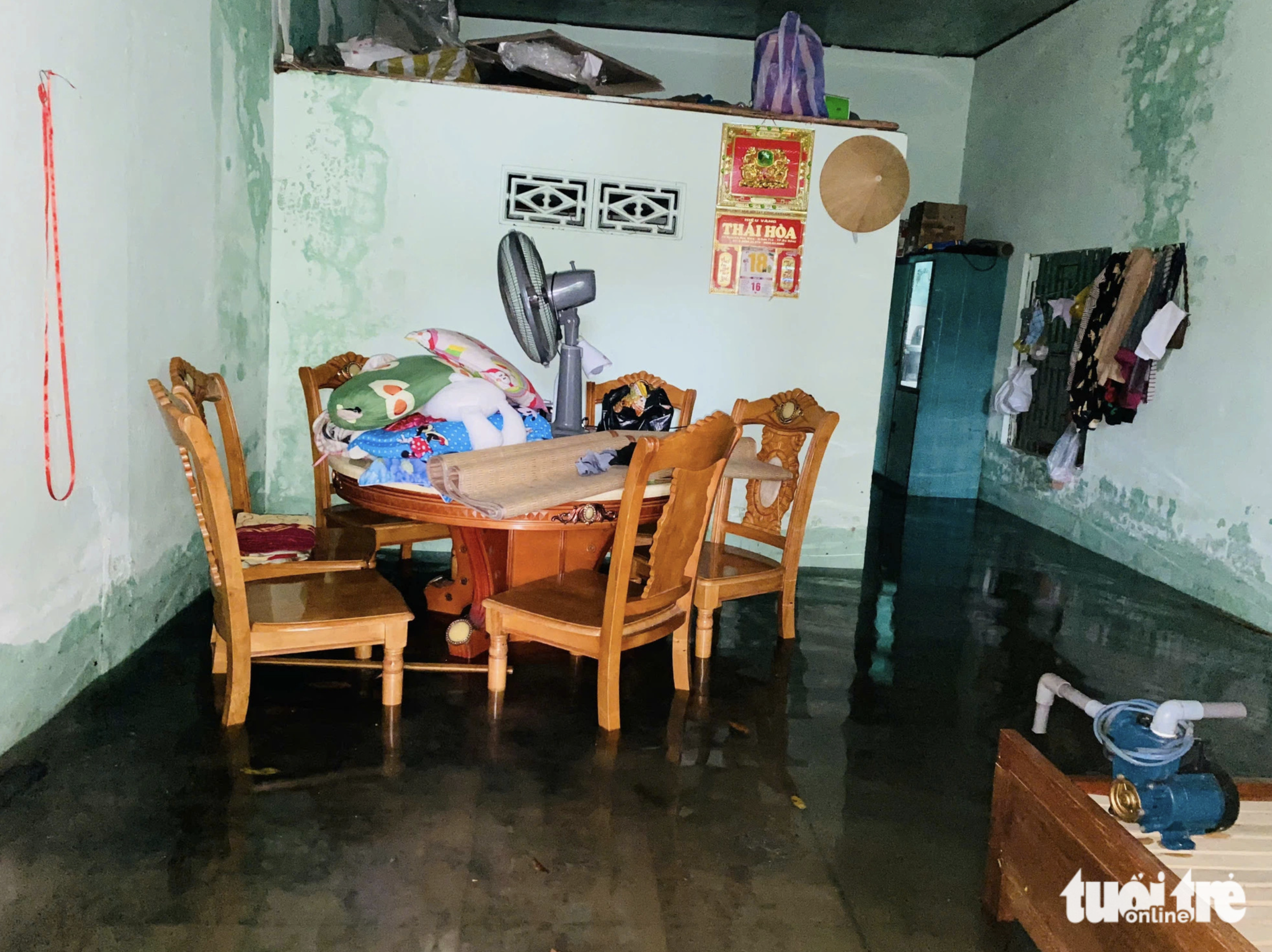 Bed sheets, blankets and an electric fan are put to higher ground as a house is submerged after heavy rain in Da Nang City. Photo: Doan Nhan / Tuoi Tre