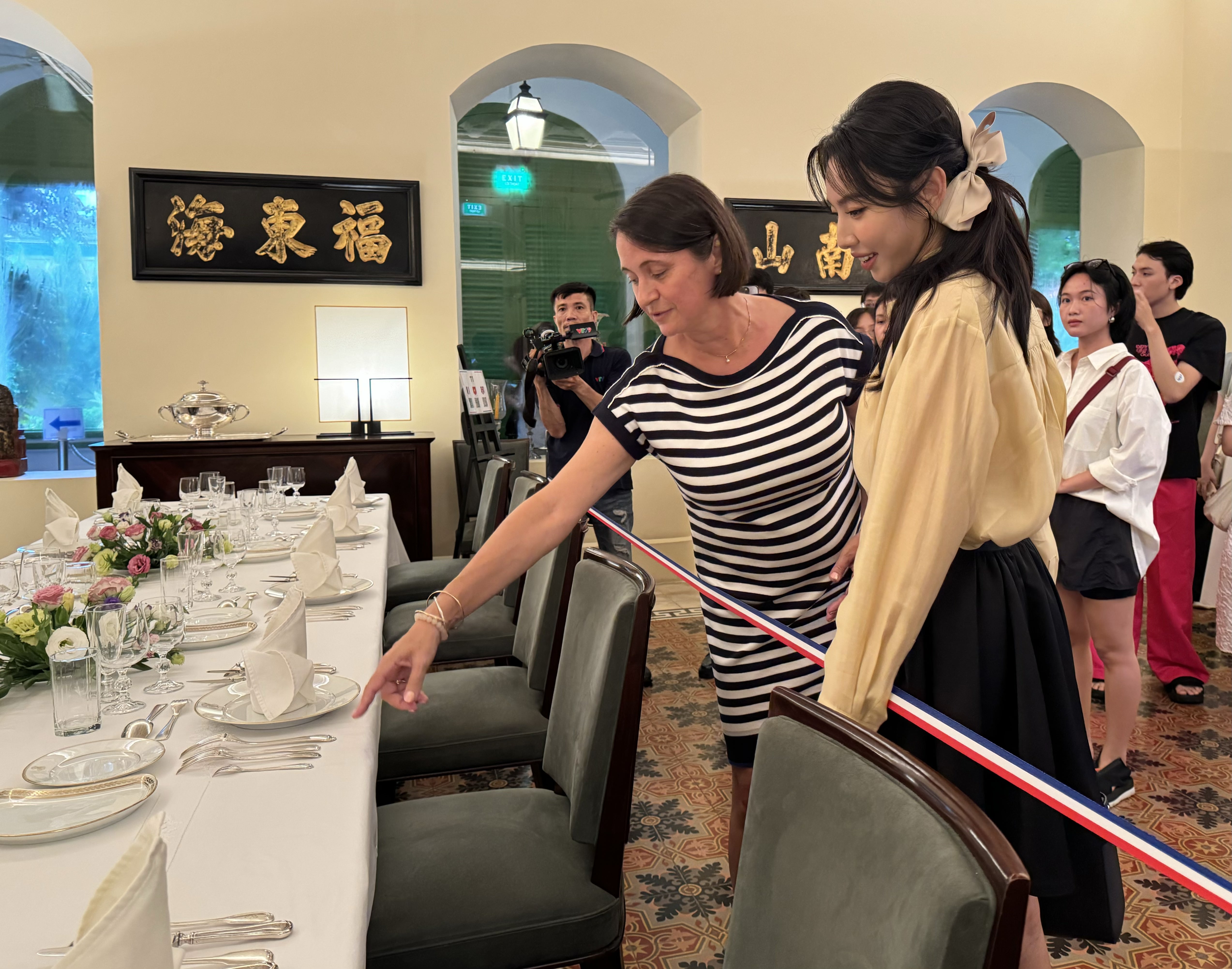 French Consul General in Ho Chi Minh City Emmanuelle Pavillon-Grosser instructs Miss Grand International 2021 Thuy Tien to set up a French-style banquet table. Photo: Minh Khoi / Tuoi Tre News