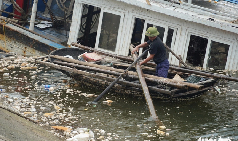 A resident fishes out garbage at the Tuan Chau international passenger port. Photo: Ngoc An / Tuoi Tre