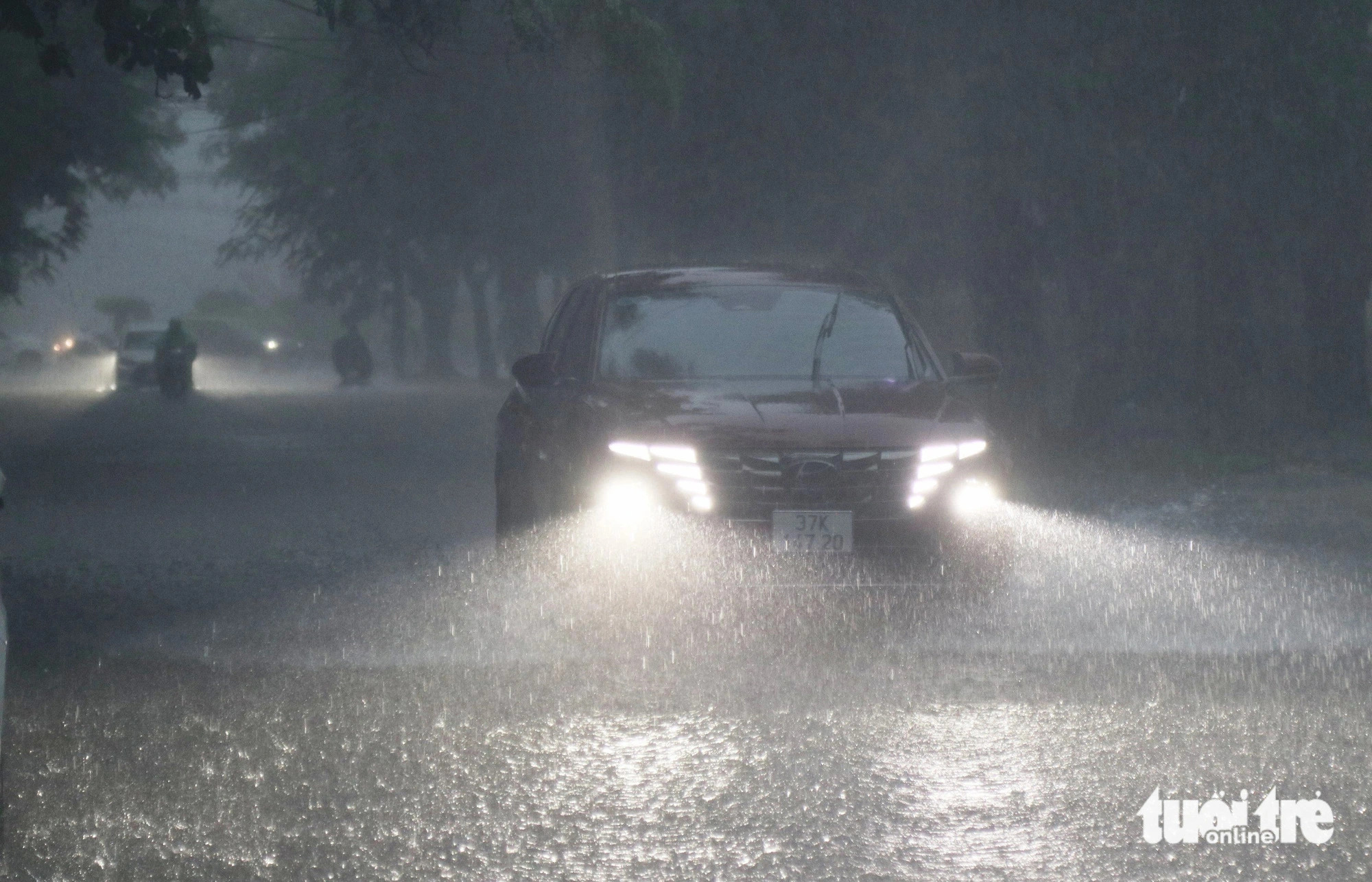 As heavy rainfall reduced visibility, a car driver turned on the headlights while traveling through a waterclogged street in Vinh City, Nghe An Province, north-central Vietnam in the morning of September 23, 2024. Photo: Doan Hoa / Tuoi Tre