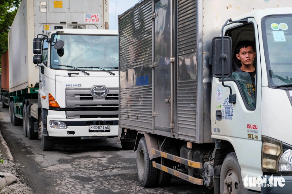 During rush hour, trucks move at a snail’s pace on a pothole-ridden section of Nguyen Van Linh Street, District 7, Ho Chi Minh City. Photo: Phuong Nhi / Tuoi Tre