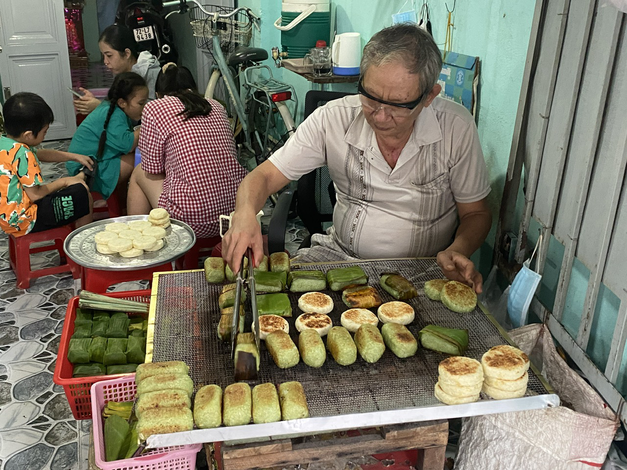 Dung, Pham Thi Phuong's husband, grills bananas wrapped in sticky rice and cassava cakes at their shop on Ba Huyen Thanh Quan Street in Vung Tau City, Ba Ria-Vung Tau Province, southern Vietnam. Photo: Dang Khuong / Tuoi Tre