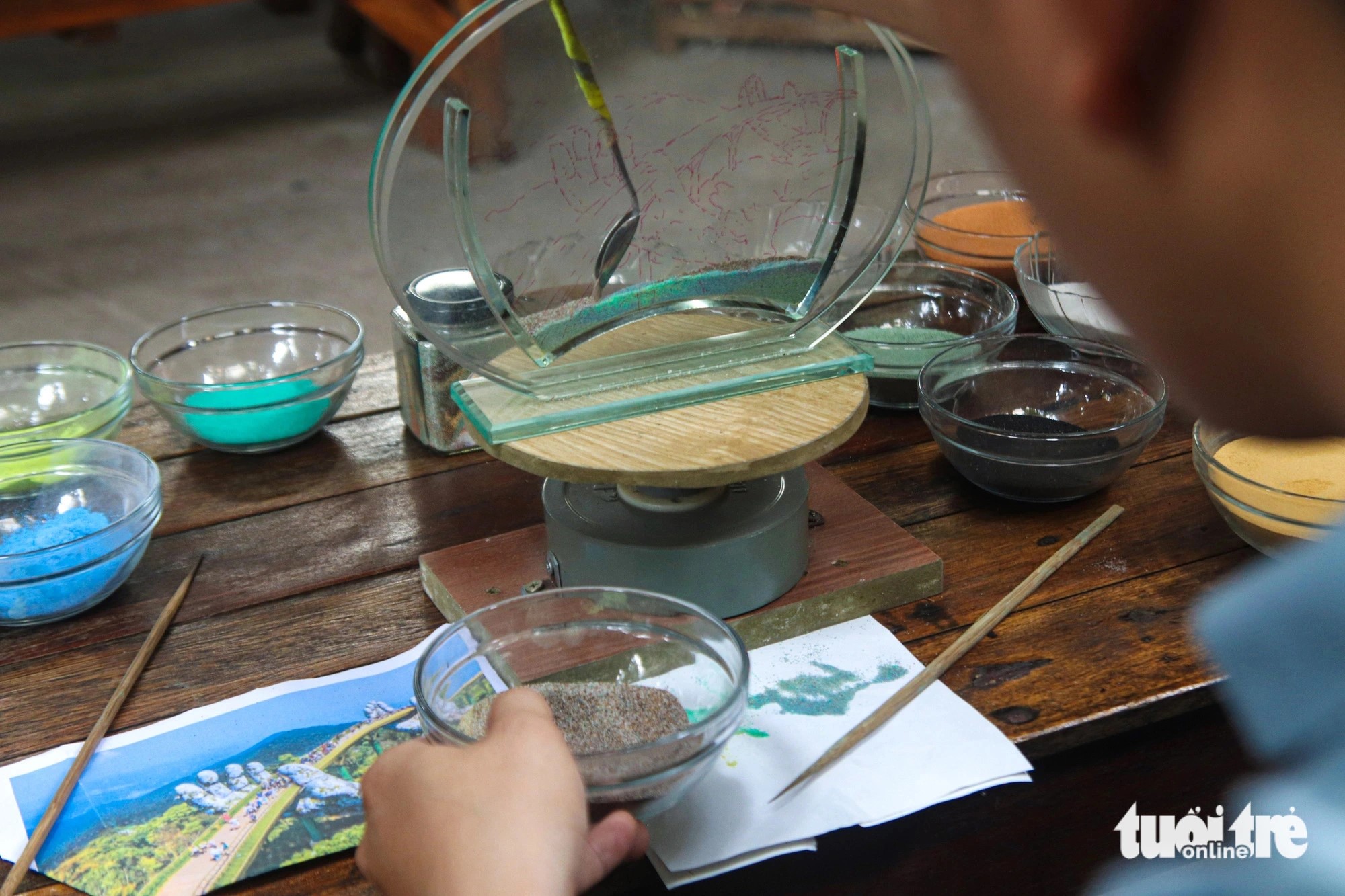 Dung skillfully arranges colorful grains of sand into a container using a bamboo stick and a specialized spoon - Photo: Thanh Nguyen / Tuoi Tre