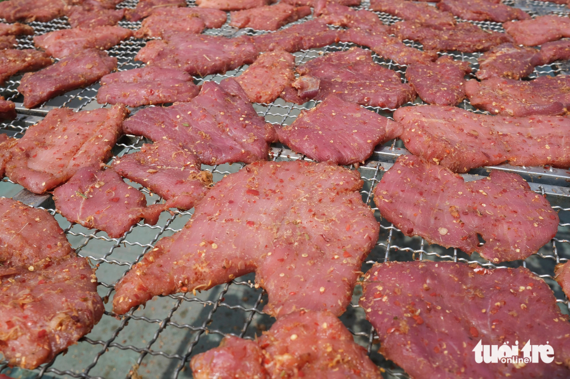 Fresh, tender pieces of beef marinated in fragrant spices gradually wilt under the hot sun. Photo: Tan Luc / Tuoi Tre