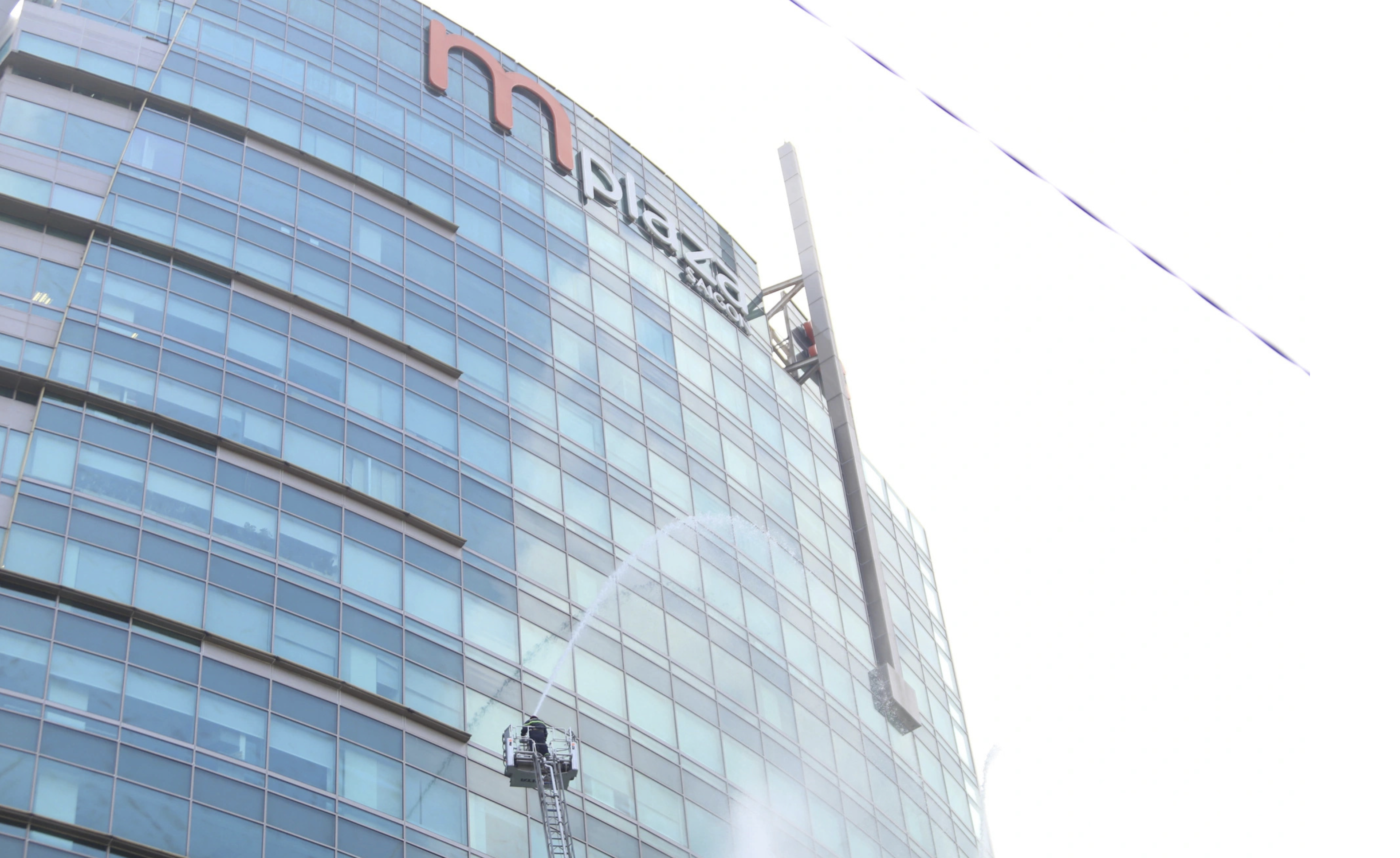 Firefighters use ladder trucks to spray water to extinguish the fire occurring at the mPlaza Saigon building in Ho Chi Minh City during a fire drill on October 4, 2024. The building covers an area of 146,000 square meters, features 21 floors and three basements, and is 91.5 meters tall. It can accommodate up to 6,000 people during rush hour. Photo: Minh Hoa / Tuoi Tre