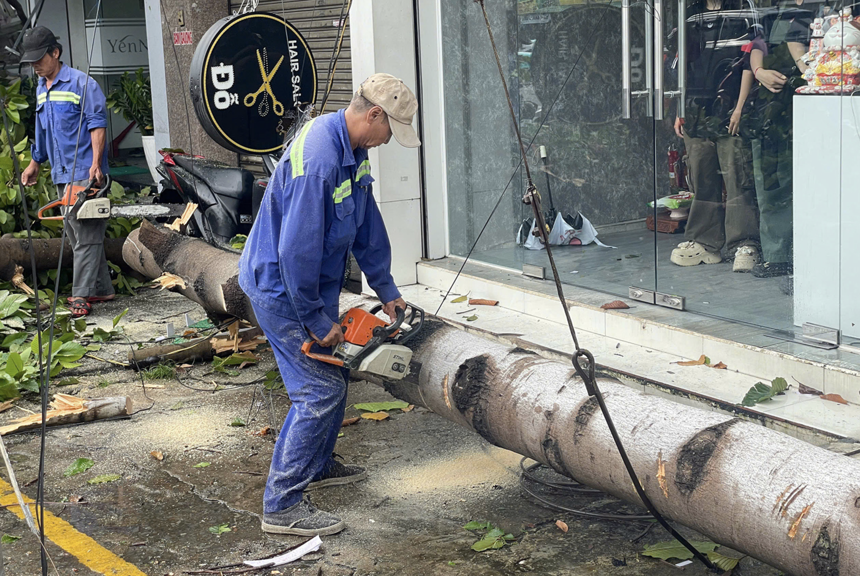 A sanitation worker splits a fallen tree into pieces on a local street in Dong Nai Province, southern Vietnam. Photo: An Binh / Tuoi Tre