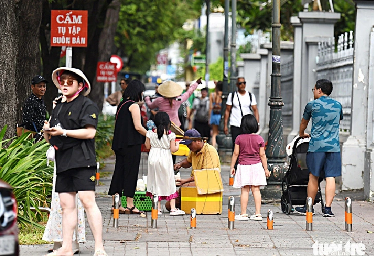 Street vendors sell products on a crowded sidewalk despite peddling banning signs in Ho Chi Minh City.