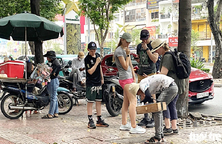 A group of tourists appear shocked when a local shoeshine touches their shoes in Ho Chi Minh City.