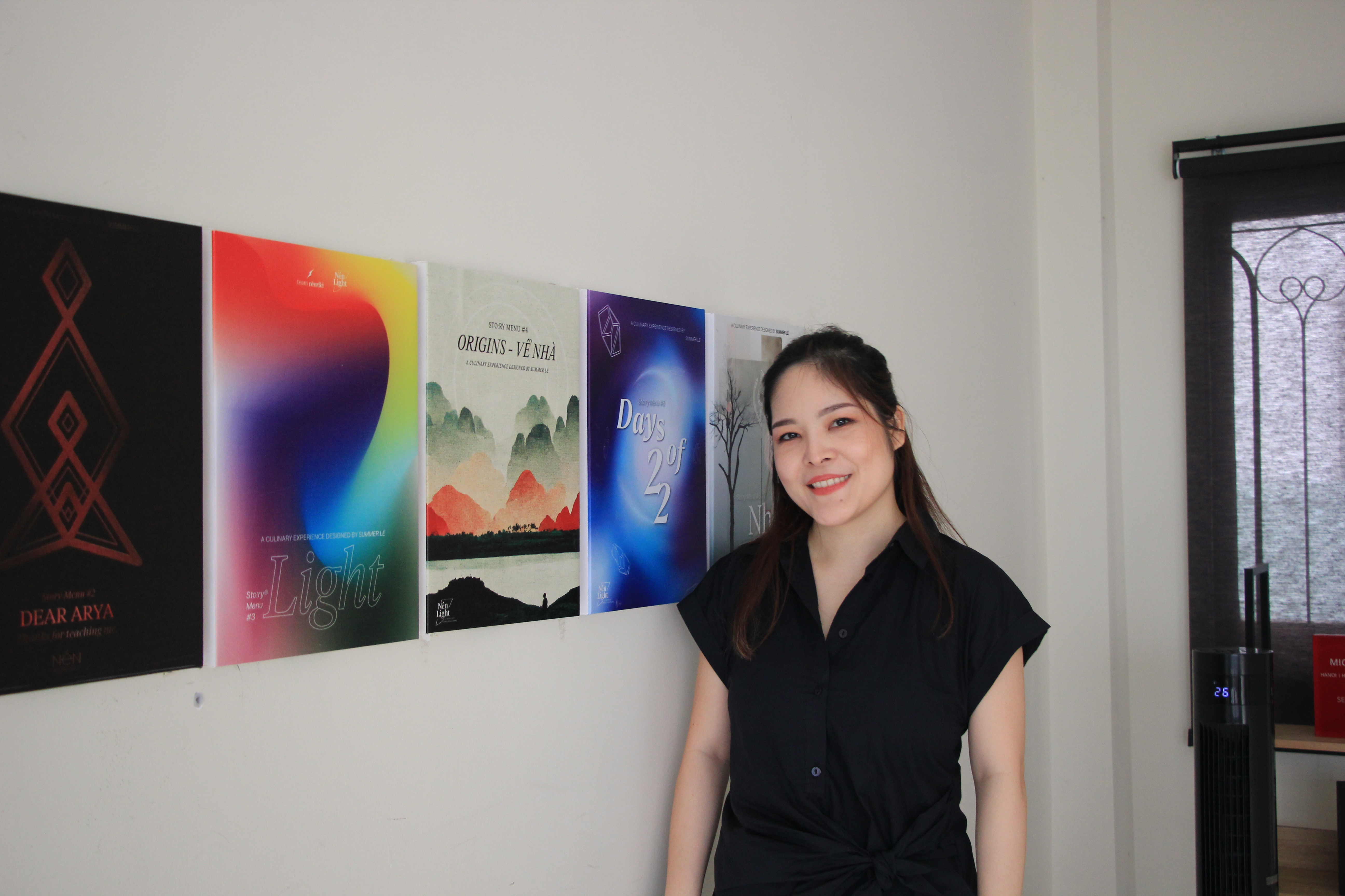 Summer Le poses with the promo photos of Nén's Sto:ry Menu concepts displayed at Nén Light Saigon in Ho Chi Minh City. Photo: Dong Nguyen / Tuoi Tre News