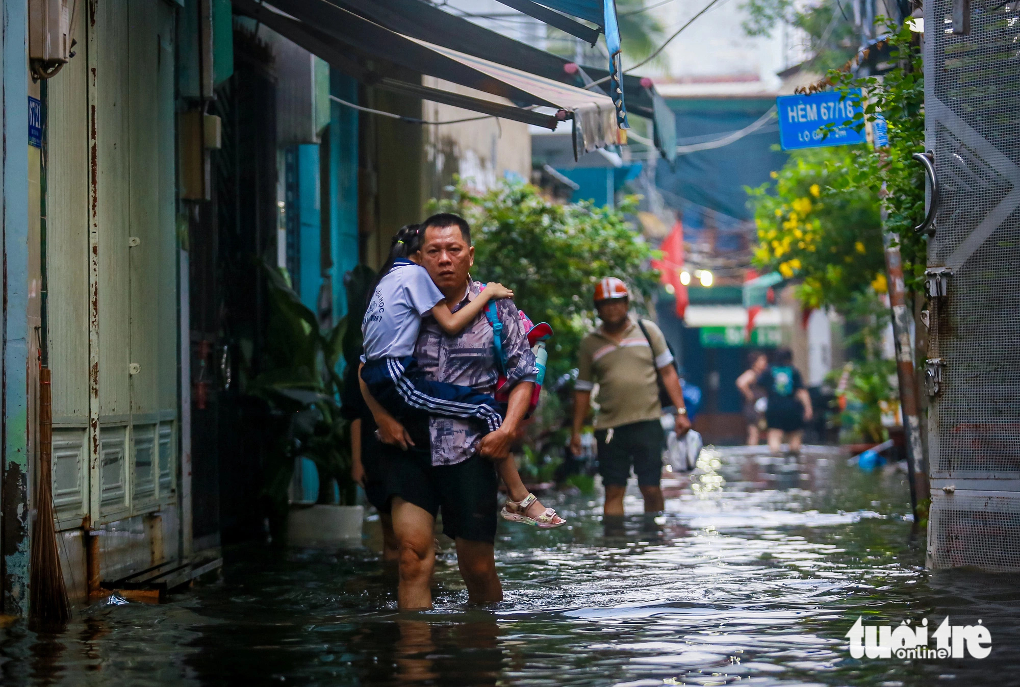 A man wades through floodwaters carrying his daughter to school down Alley 67 on Bui Van Ba Street in District 7, Ho Chi Minh City, October 18, 2024. Photo: Le Phan / Tuoi Tre