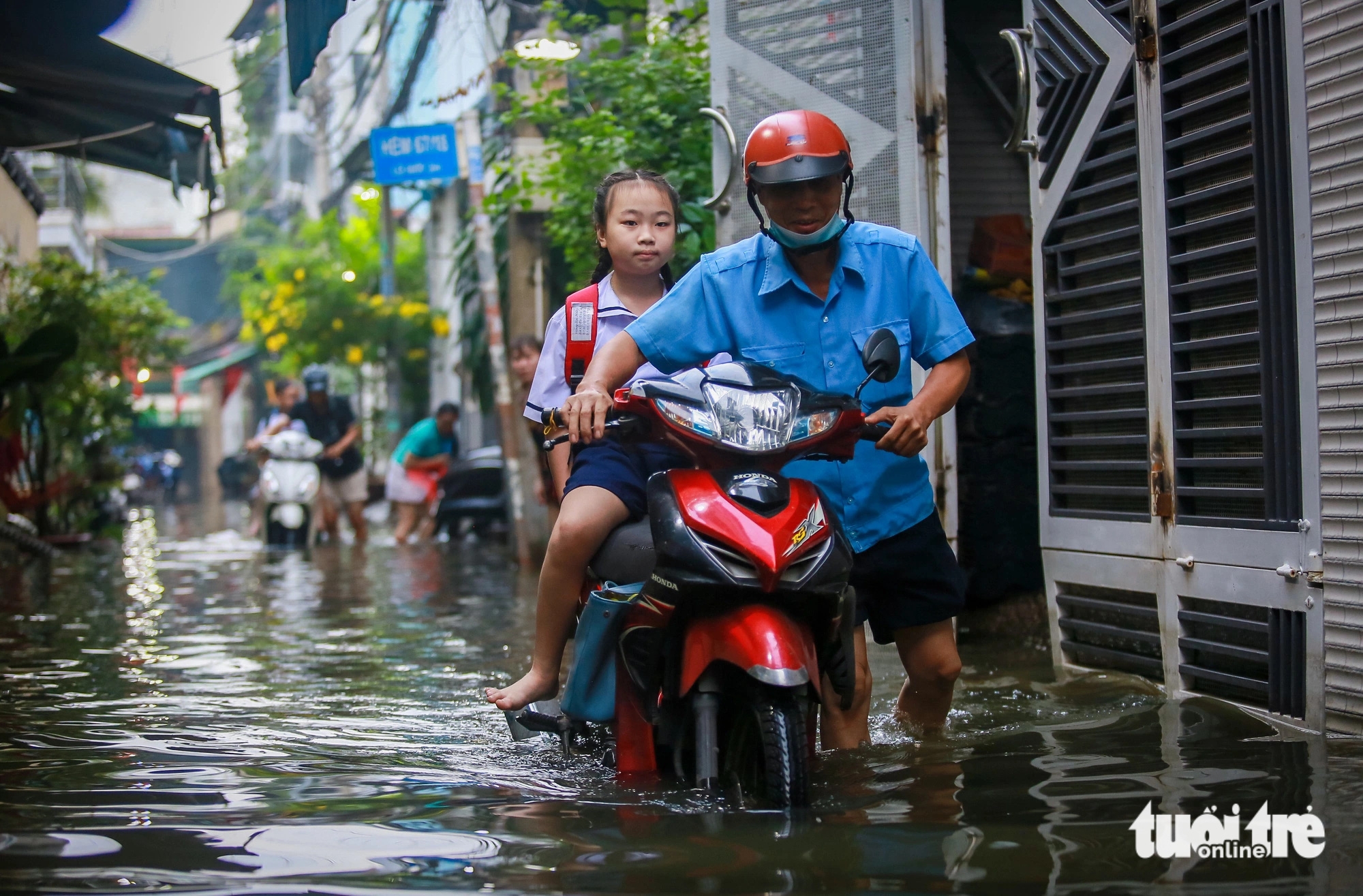 A man wades through floodwaters carrying his daughter to school down Alley 67 on Bui Van Ba Street in District 7, Ho Chi Minh City, October 18, 2024. Photo: Chau Tuan / Tuoi Tre