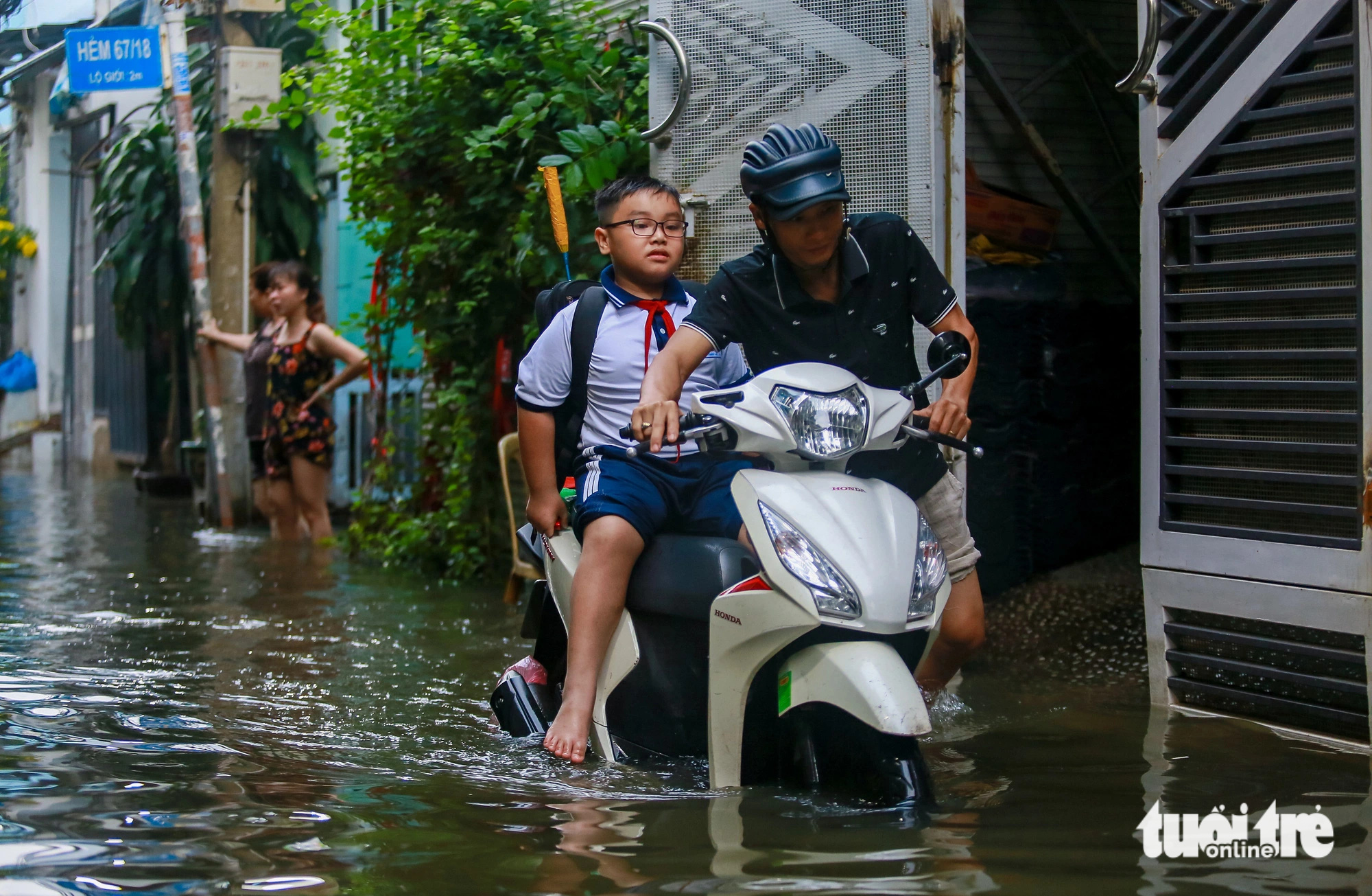 A man wades through floodwaters carrying his son to school down Alley 67 on Bui Van Ba Street in District 7, Ho Chi Minh City, October 18, 2024. Photo: Chau Tuan / Tuoi Tre