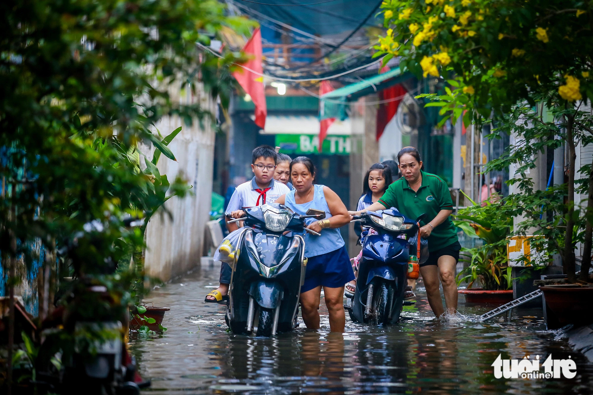 Parents wade through floodwaters carrying their children to school down Alley 67 on Bui Van Ba Street in District 7, Ho Chi Minh City, October 18, 2024. Photo: Chau Tuan / Tuoi Tre