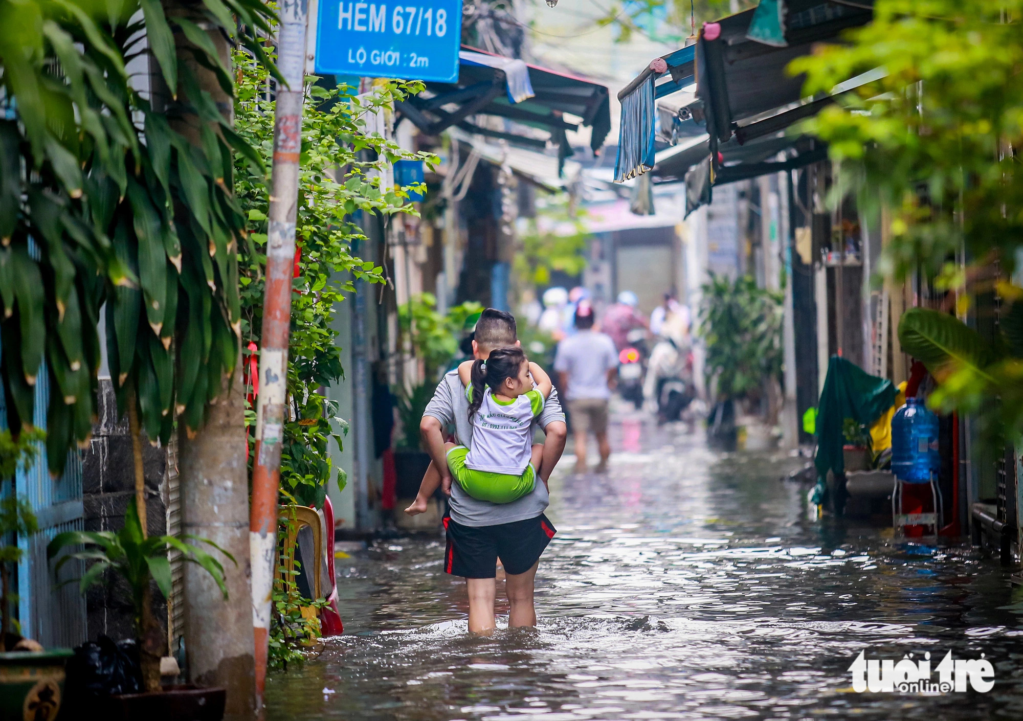 A man wade through floodwaters carrying his daughter to school down Alley 67 on Bui Van Ba Street in District 7, Ho Chi Minh City, October 18, 2024. Photo: Le Phan / Tuoi Tre