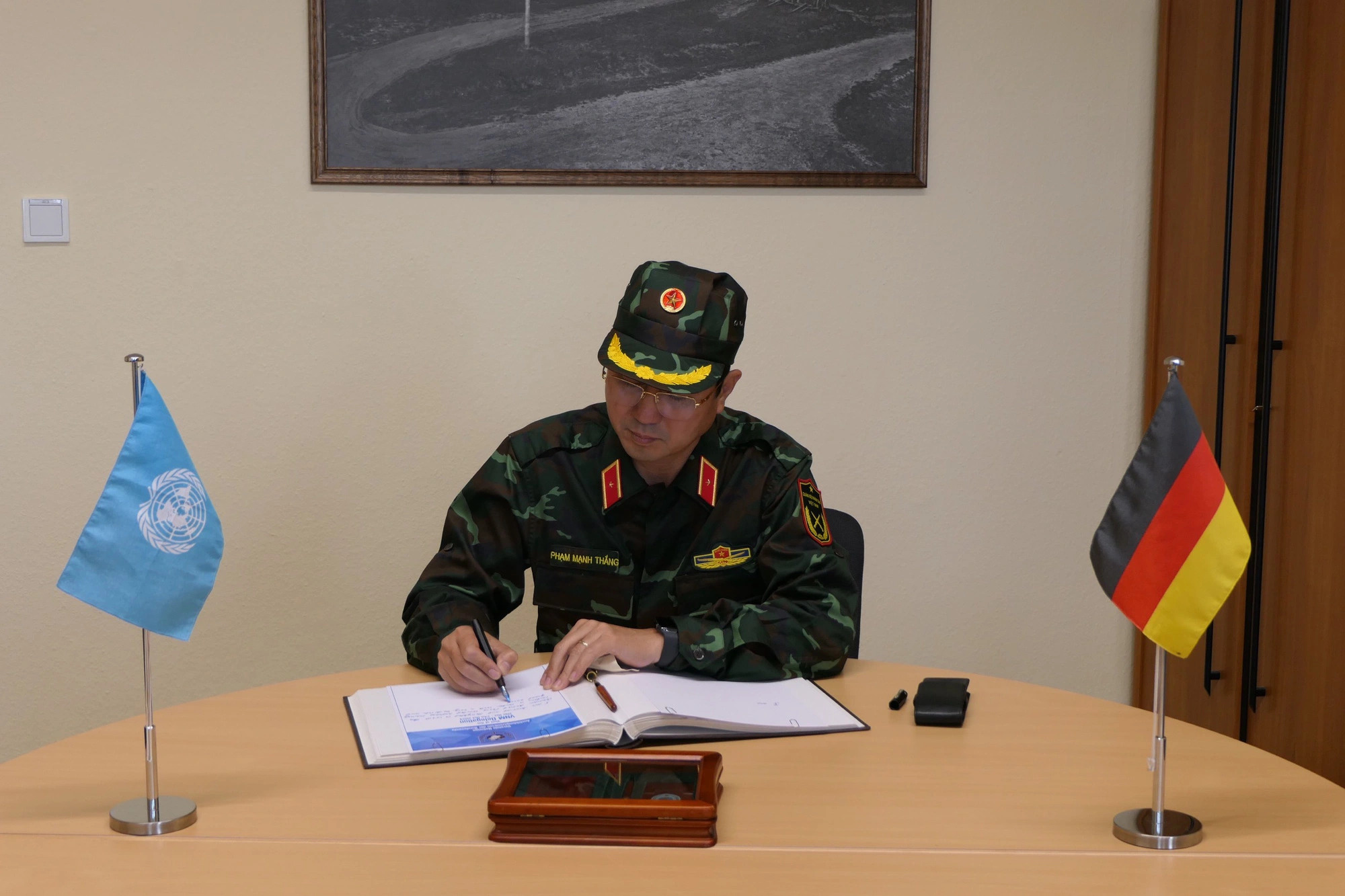 Major General Pham Manh Thang (C), chief of the Vietnam Department of Peacekeeping Operations, writes in a guestbook during his visit to Germany from October 20 to 23, 2024. Photo: Vietnam Department of Peacekeeping Operations