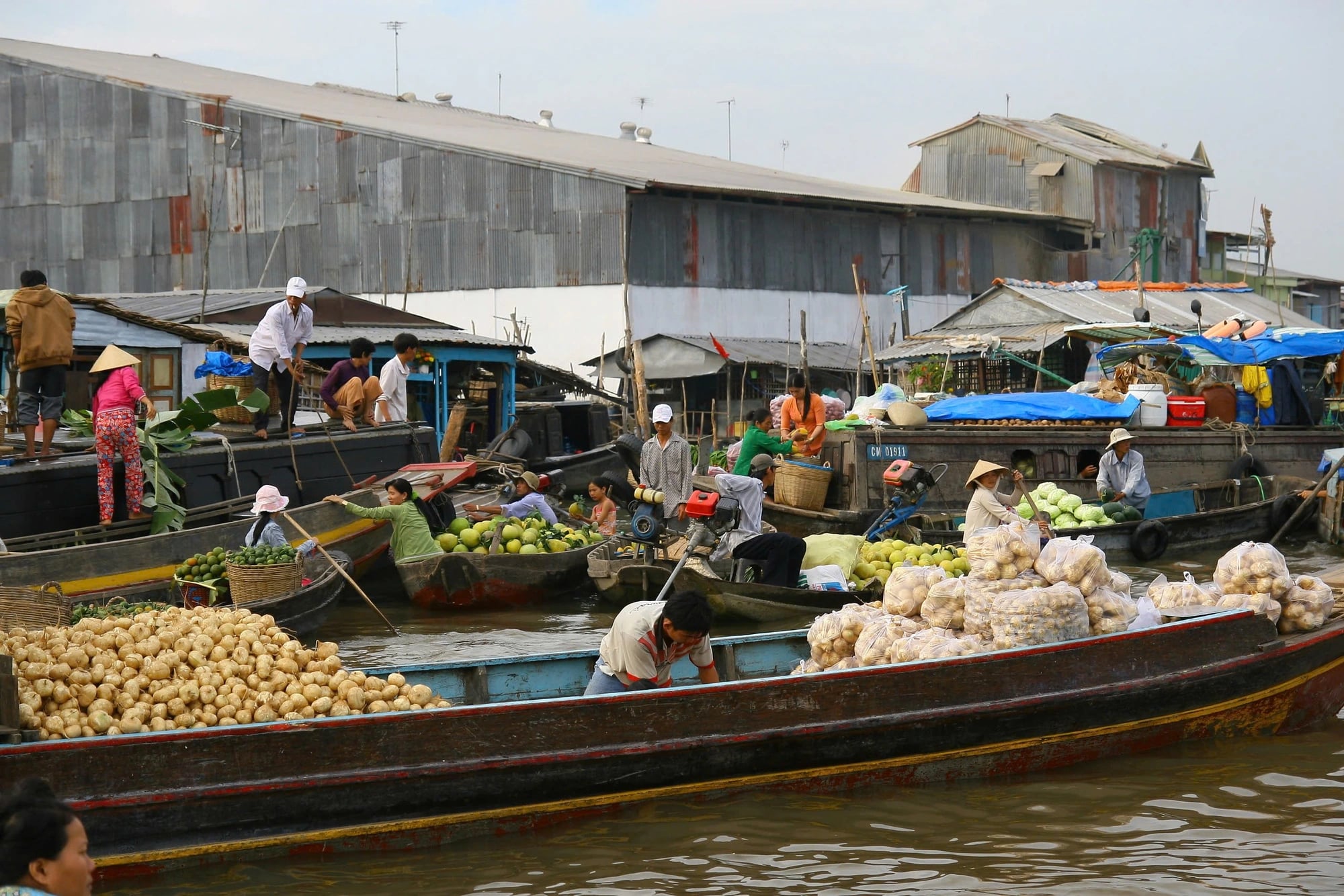 Diverse goods fill boats, creating a vibrant atmosphere at a floating market in the Mekong Delta.