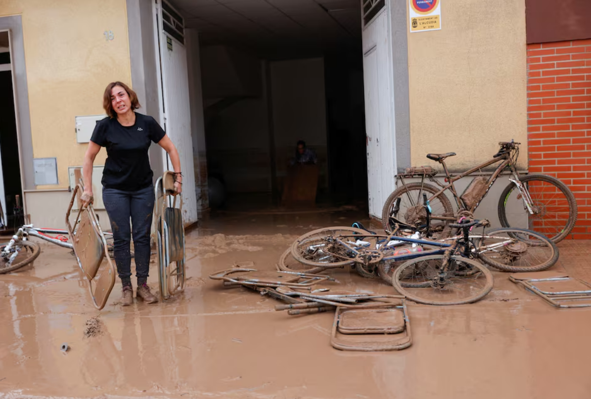 A woman carries out folding chairs caked in mud after torrential rains caused flooding in La Alcudia, Valencia region, Spain, October 30, 2024. Photo: Reuters