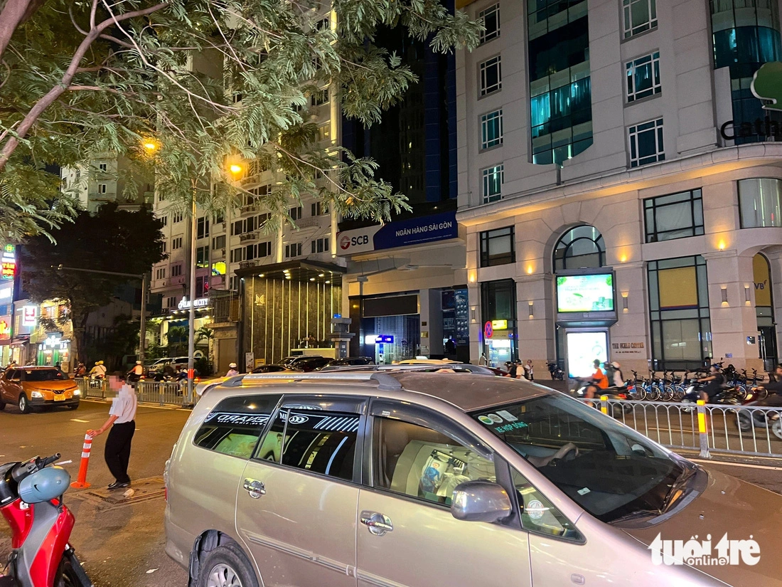 A security guard at a store on Pham Hong Thai Street in District 1, Ho Chi Minh City puts traffic cones on the street to save space for customer parking. Photo: Dieu Qui / Tuoi Tre