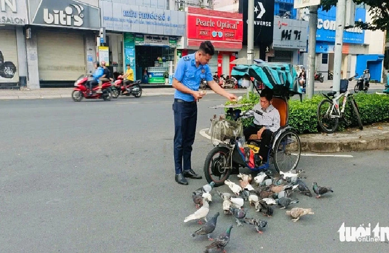 A security guard at Le Van Tam Park in District 1, Ho Chi Minh City buys lottery tickets from Binh. Everyone at the park is familiar with the scene of Binh feeding pigeons. Photo: Trung Dan / Tuoi Tre