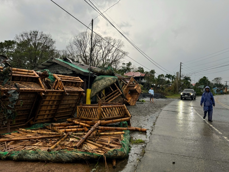 A resident walks past a destroyed bamboo house after it was blown off along a highway in Cagayan Province. Photo: AFP