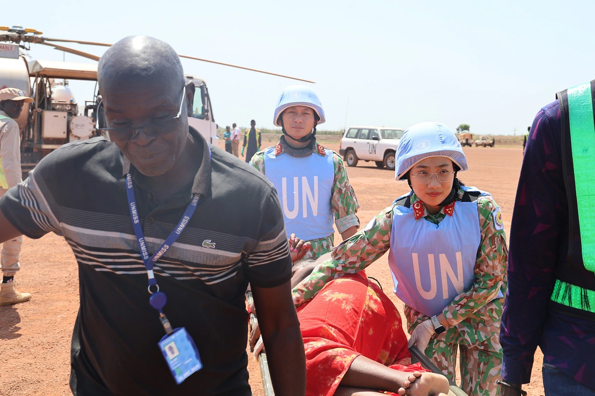 Two Vietnamese medical staff members (R, 2nd and 3rd) from Vietnam’s Level-2 Field Hospital Rotation 6 under the United Nations Mission in South Sudan are pictured assisting in carrying a Kenyan pregnant woman at risk of extreme preterm labor, who required urgent medical treatment. Photo: Vietnam Department of Peacekeeping Operations