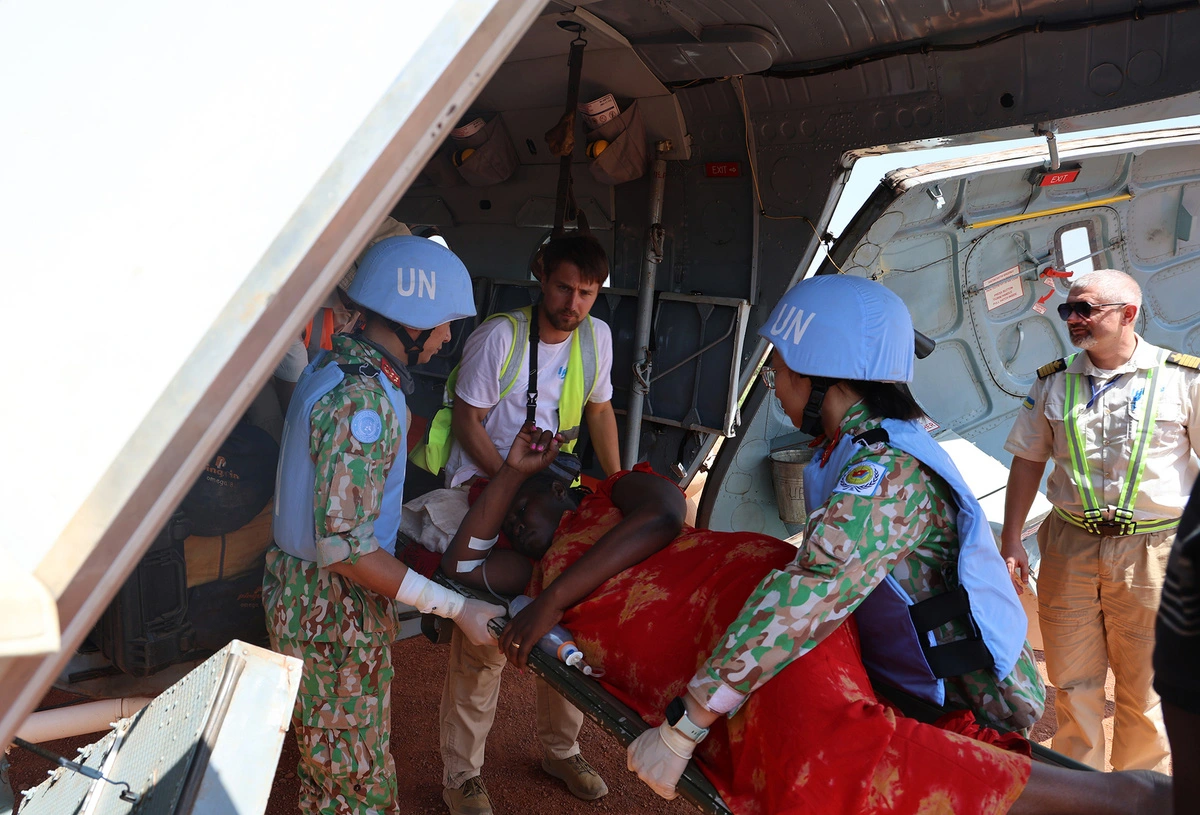 Two Vietnamese medical staff members, wearing UN peacekeeping helmets, from Vietnam’s Level-2 Field Hospital Rotation 6 under the United Nations Mission in South Sudan are seen helping transport a Kenyan pregnant woman on a plane, en route to a hospital for emergency treatment. Photo: Vietnam Department of Peacekeeping Operations