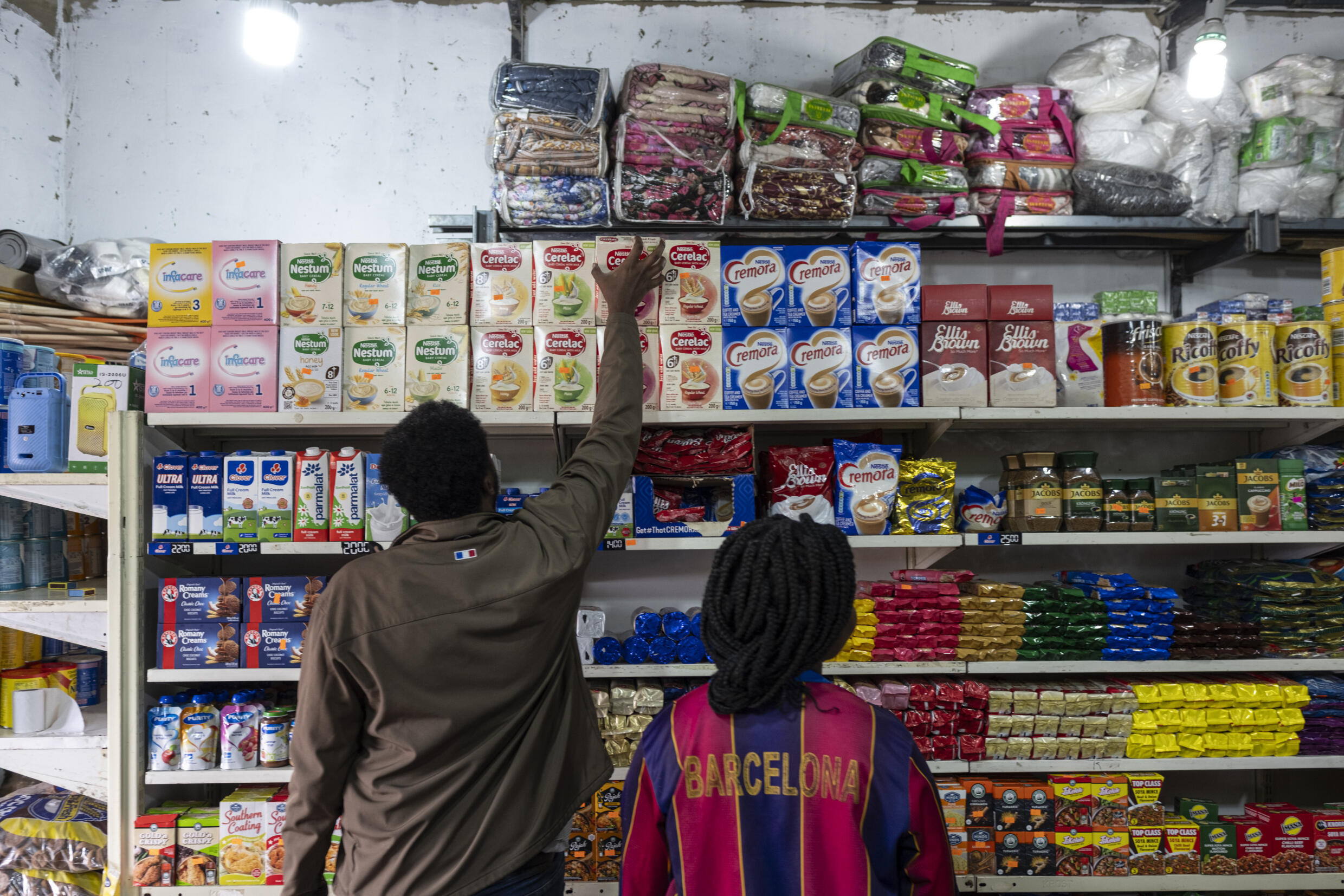 A worker grabs an item from a shelf for a client in a spaza shop (informal supermarket) in Soweto, near Johannesburg, on November 12, 2024. Photo: AFP