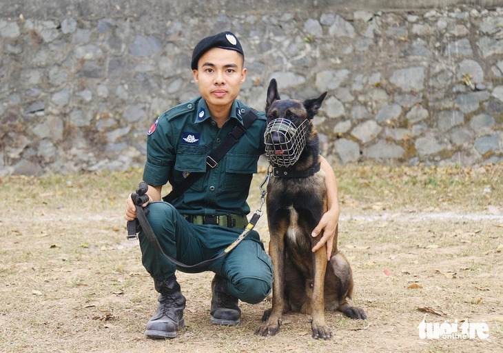 A Cambodian police officer sits down beside his dog during a performance session in Hanoi on November 25, 2024. Photo: Danh Trong / Tuoi Tre