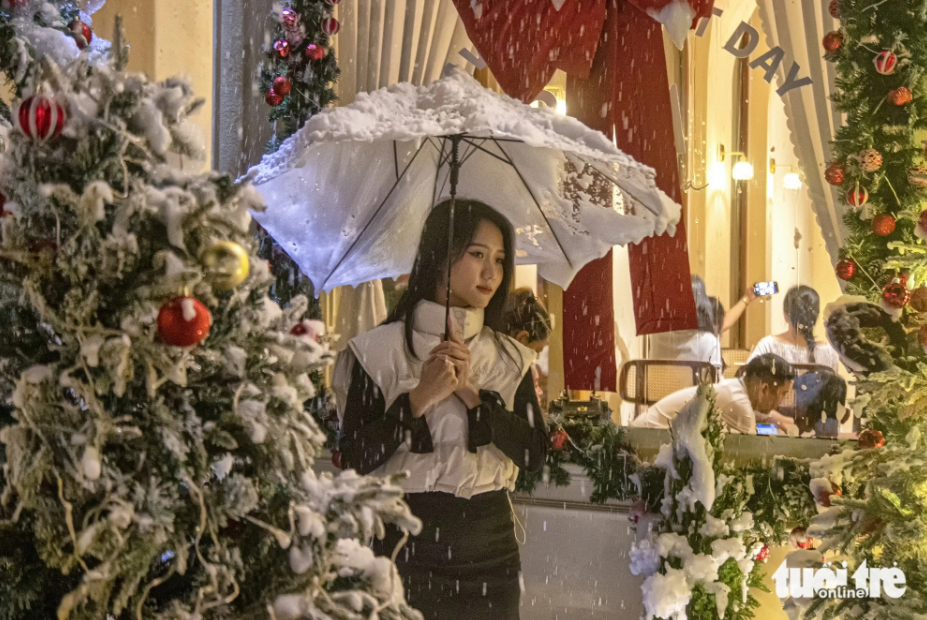 A girl poses for a photo in the snow at a Da Nang-based coffee shop equipped with an artificial snow spraying system. Photo: Thanh Nguyen / Tuoi Tre