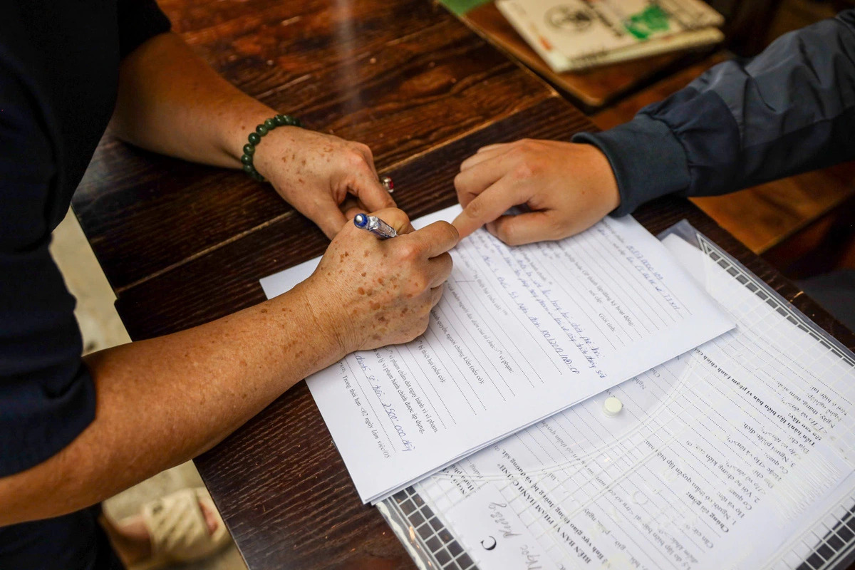 A trackside café owner in Hanoi receives a violation notice and signs a pledge not to repeat the offense. Photo: D. Tien / Tuoi Tre