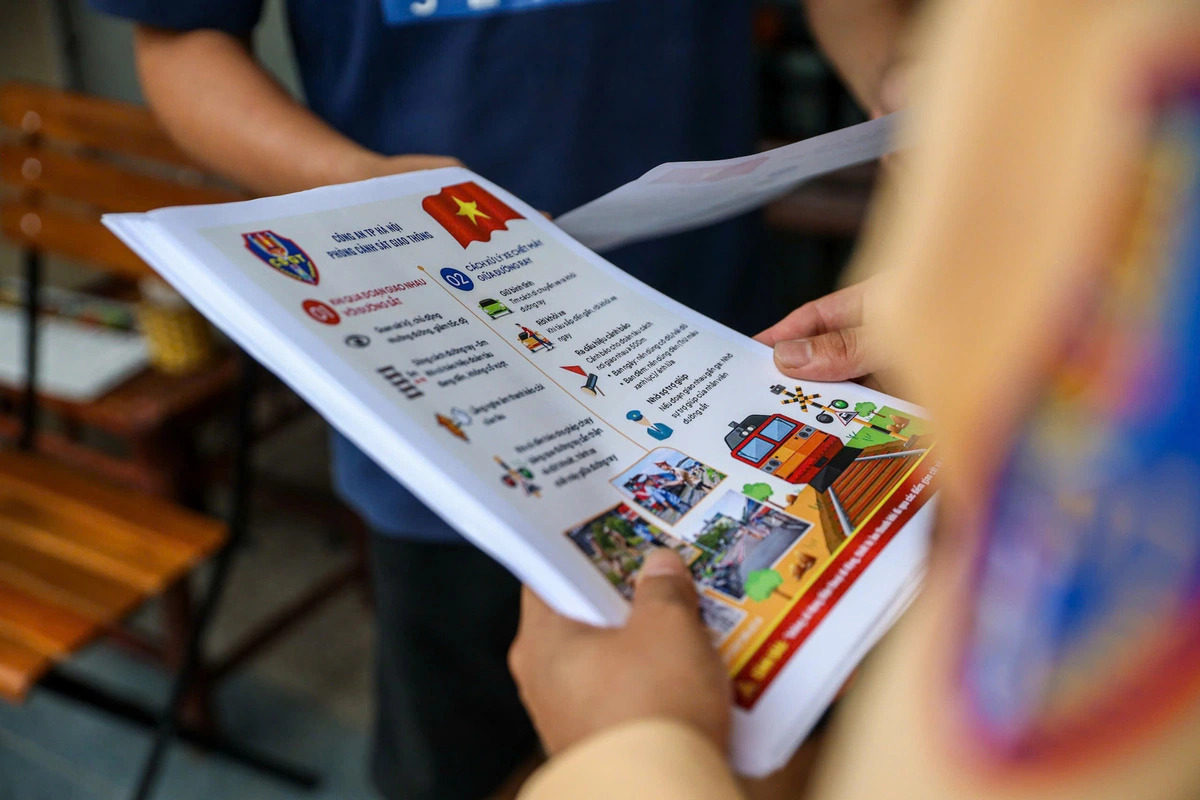 Railway safety instructions and warnings are distributed to residents and tourists in Hanoi’s trackside café area. Photo: D. Tien / Tuoi Tre