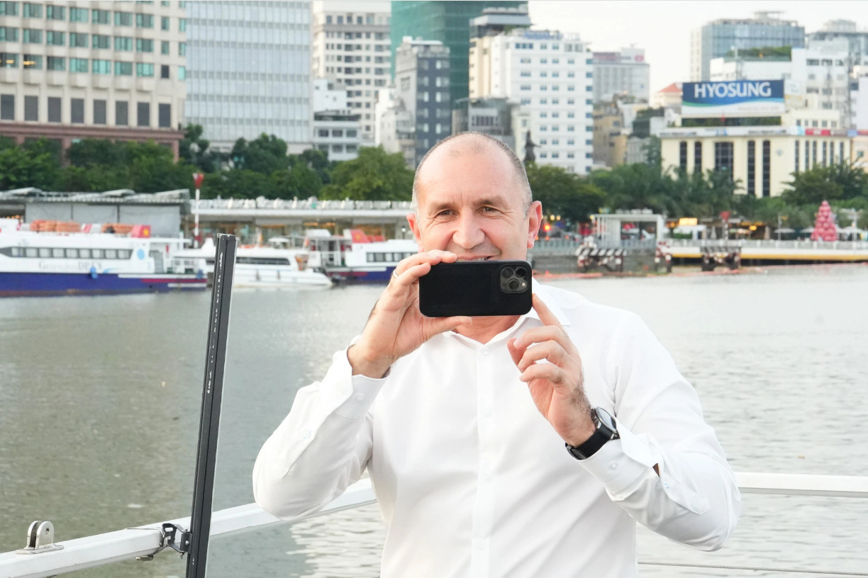 Bulgarian President Rumen Radev takes photos of Ho Chi Minh City on a water bus traveling along the Saigon River. Photo: Huu Hanh / Tuoi Tre