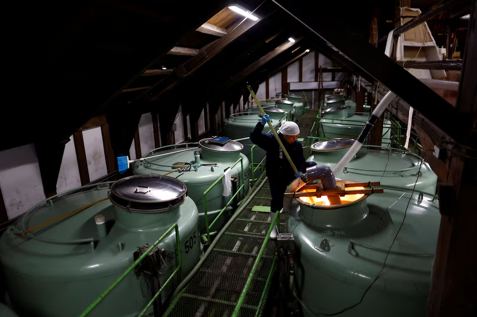 A brewer using a long paddle stirs the mixture of rice, Koji, water and yeast starter inside a giant tank as a part of the fermentation process to brew sake, a traditional Japanese rice wine, at Ishikawa Shuzou, or Ishikawa Brewery, in Fussa, western portion of Tokyo, Japan November 25, 2024. Photo: Reuters