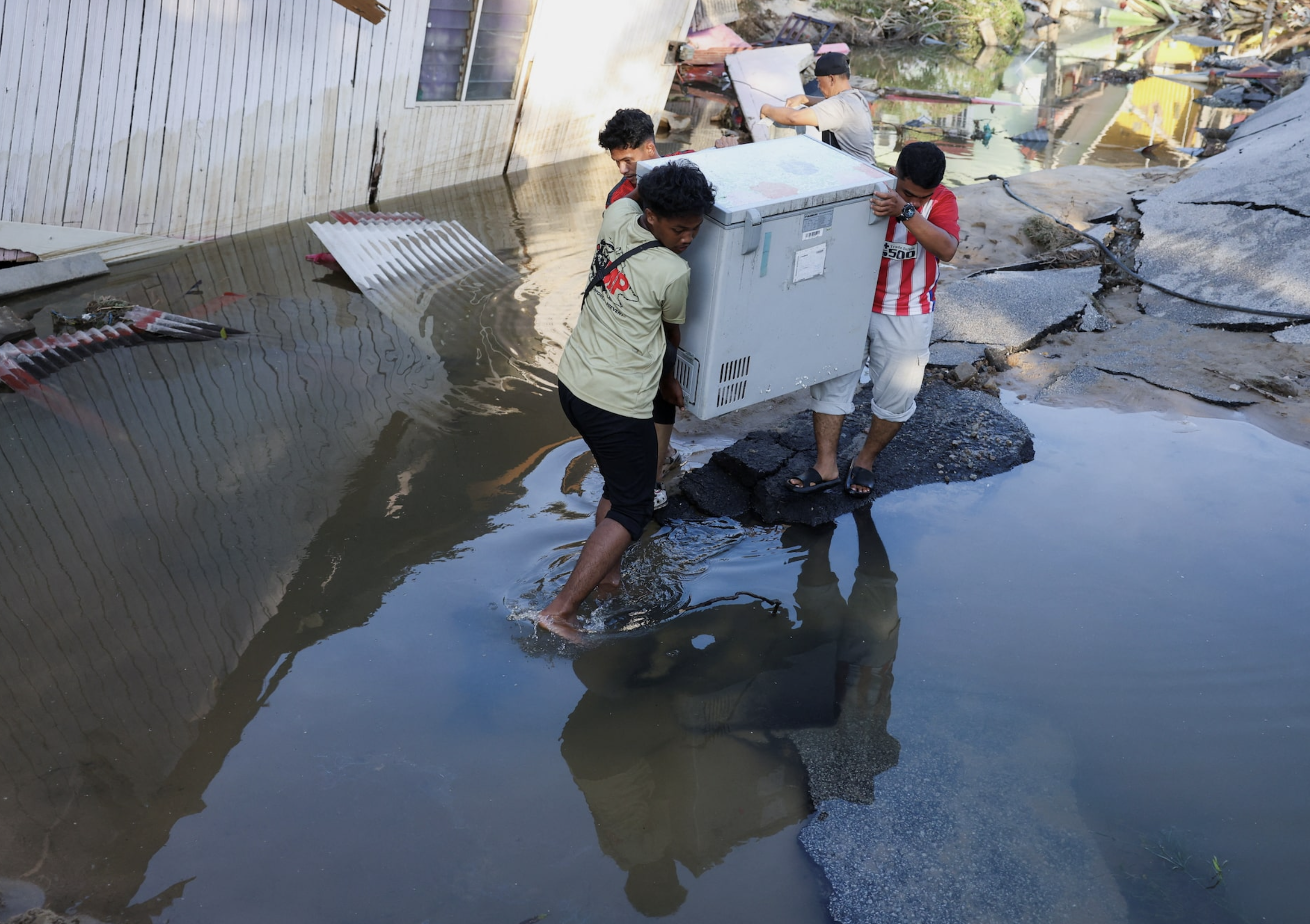 Men carry a freezer as they begin cleaning up after the floodwaters recede in Tumpat, Malaysia, December 2, 2024. Photo: Reuters