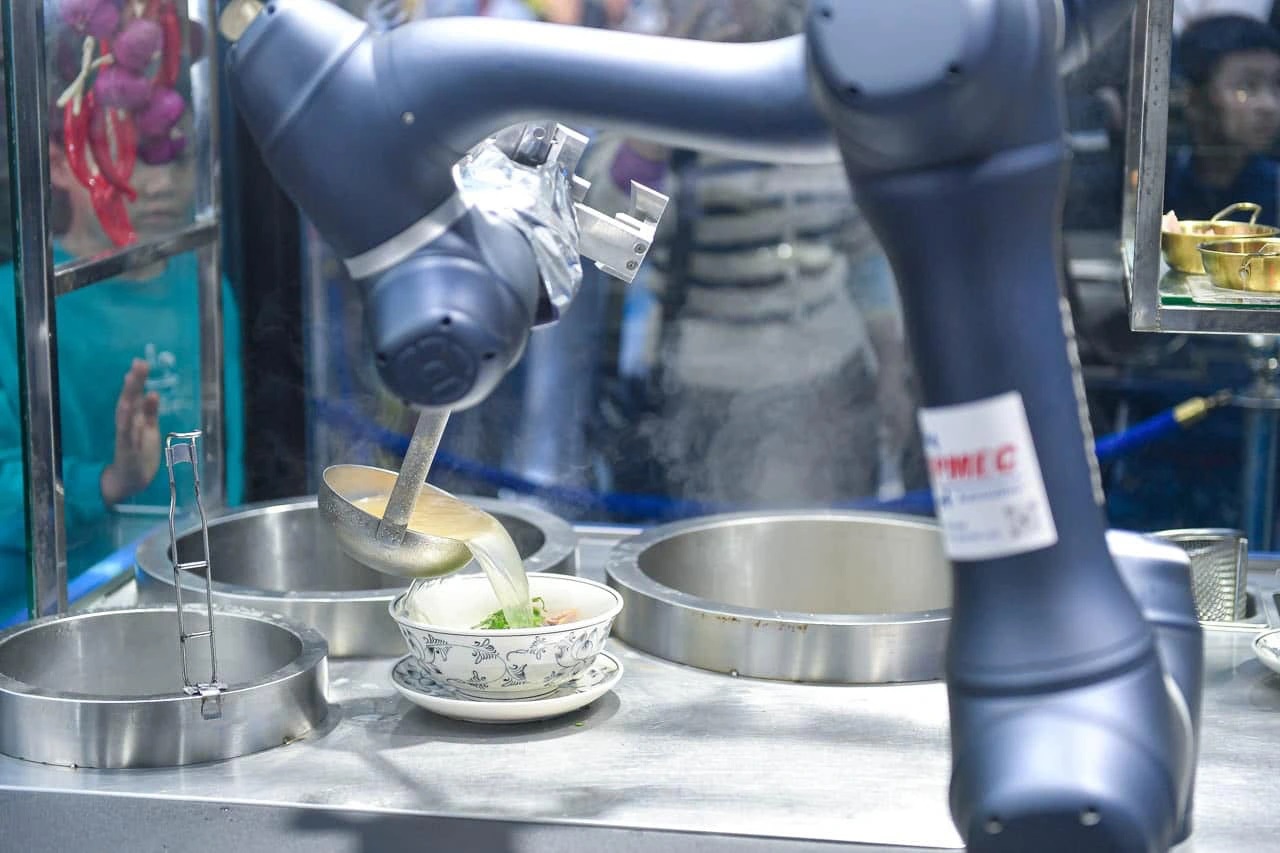 The robot skillfully ladles broth into a bowl of Phở - Photo: Quang Vien / Tuoi Tre