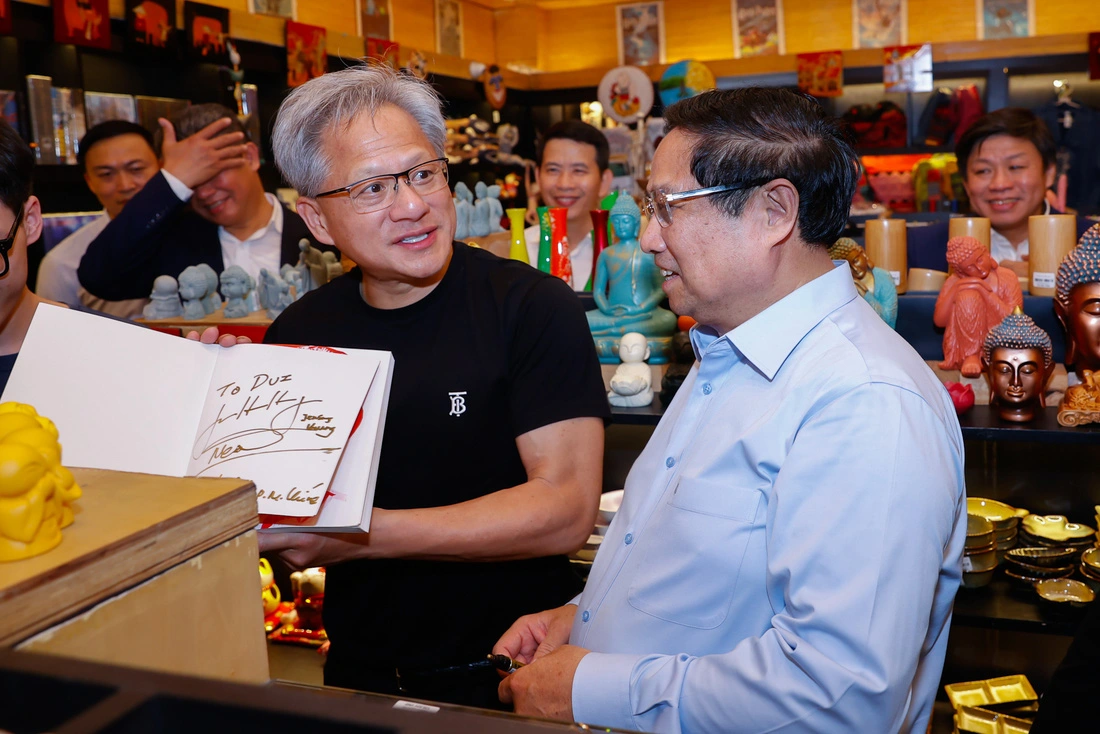 Prime Minister Pham Minh Chinh (R) and Jensen Huang (holding a book), president and CEO of Nvidia, visit a shop selling books and souvenirs in Hanoi, December 5, 2024. Photo: Doan Bac