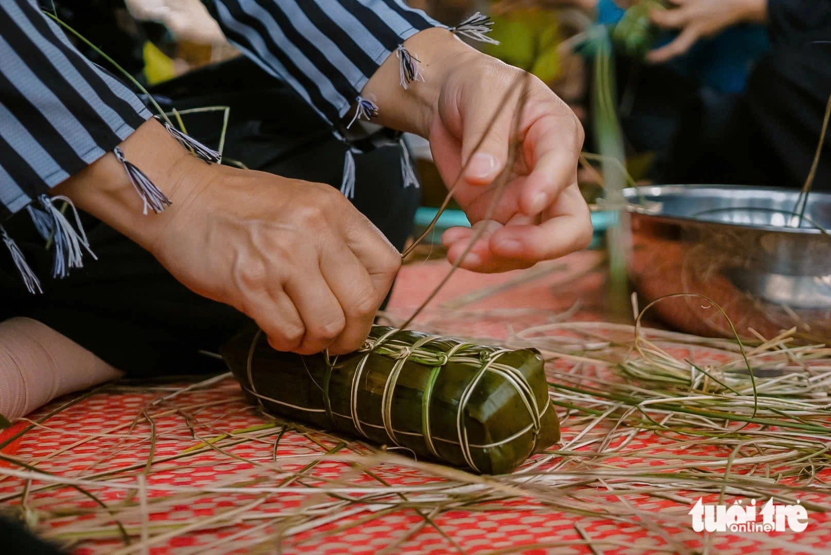 A ‘bánh tét’ is tied with banana strips before being cooked. Photo: Tong Doanh / Tuoi Tre