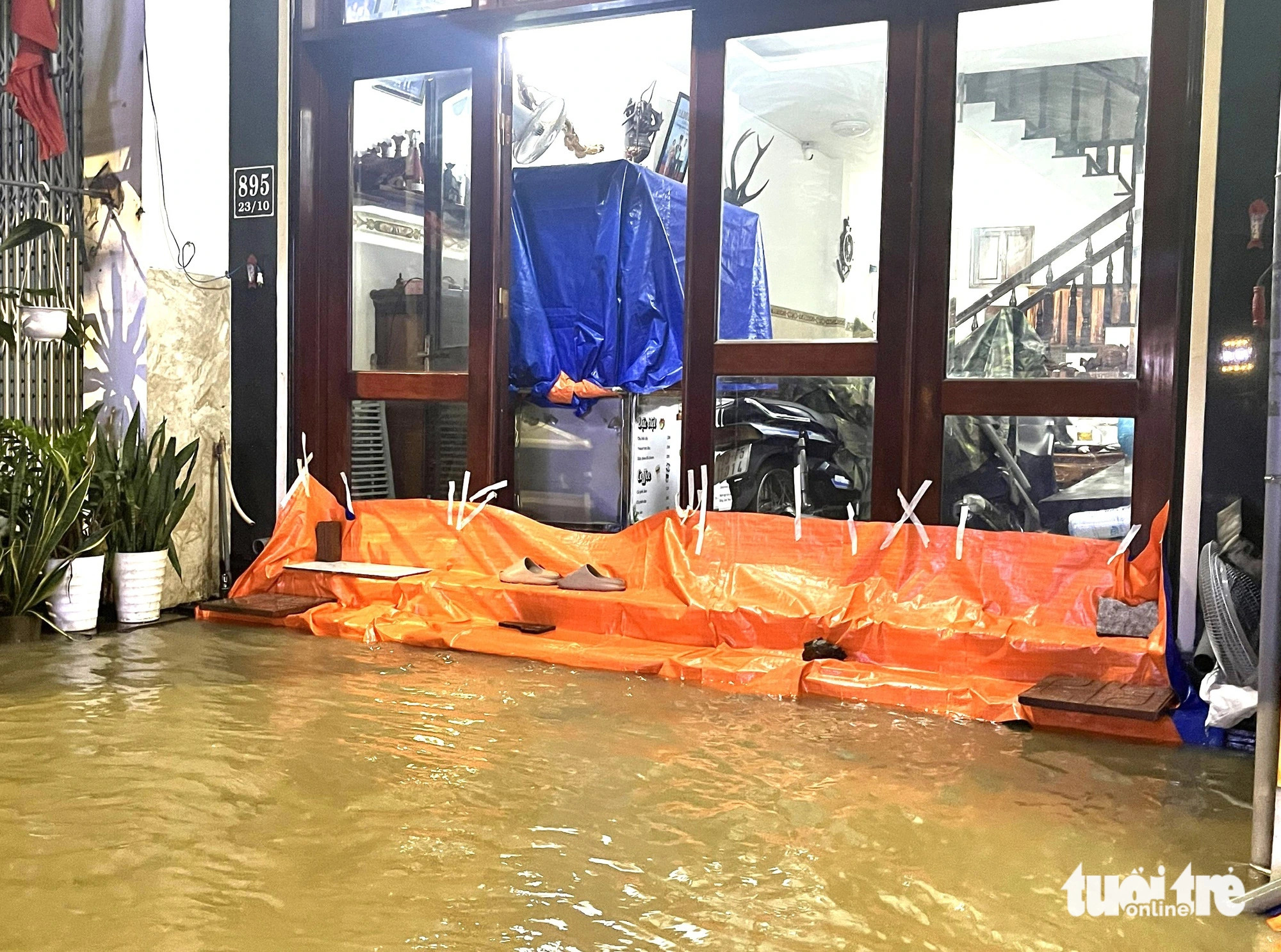 A plastic sheet tries to prevent floodwaters from entering and damaging household items, December 15, 2024. Photo: Nguyen Hoang / Tuoi Tre