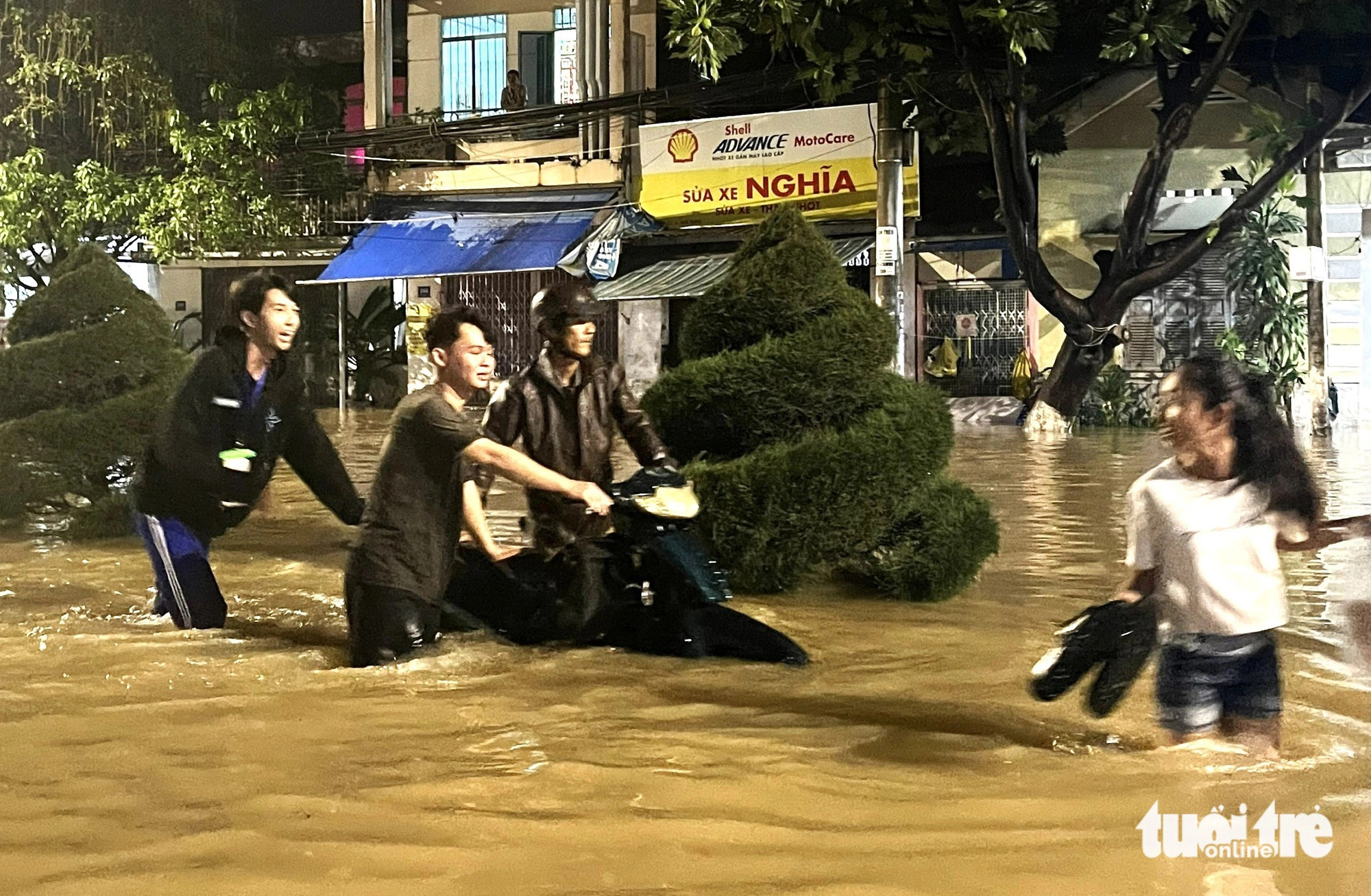 Three men push a broken motorcycle on the flooded October 23 Street in Vinh Trung Commune, Nha Trang City, December 15, 2024. Photo: Nguyen Hoang / Tuoi Tre