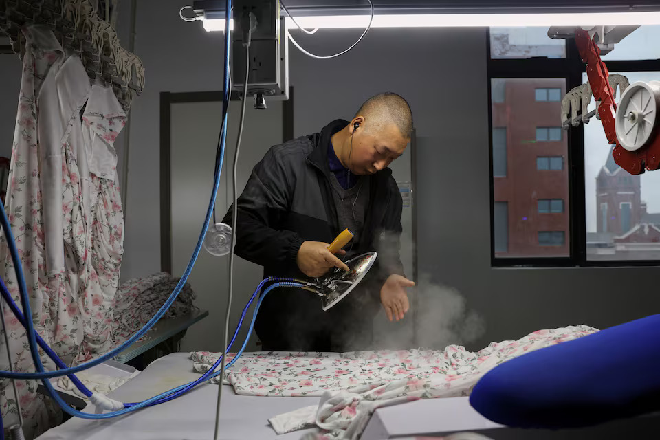 [10/10]An employee operates a clothing iron on the production line of a lingerie factory at WeMet Industrial Park, in Guanyun county of Lianyungang, Jiangsu province, China November 25, 2024. Photo: Reuters