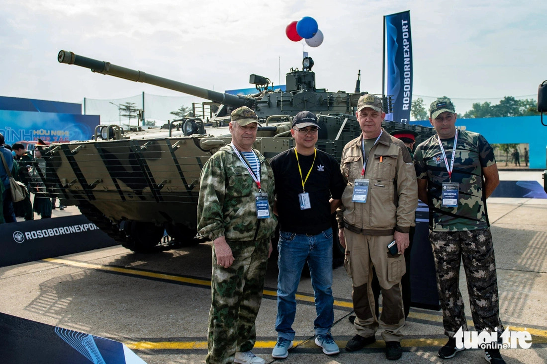 Military experts from Russian arms exporter Rosoboronexport pose for a photo in front of a BMP-3 infantry fighting vehicle at the outdoor area of the 2024 Vietnam International Defense Expo scheduled on December 19-22, 2024 in Hanoi. Photo: Nam Tran / Tuoi Tre