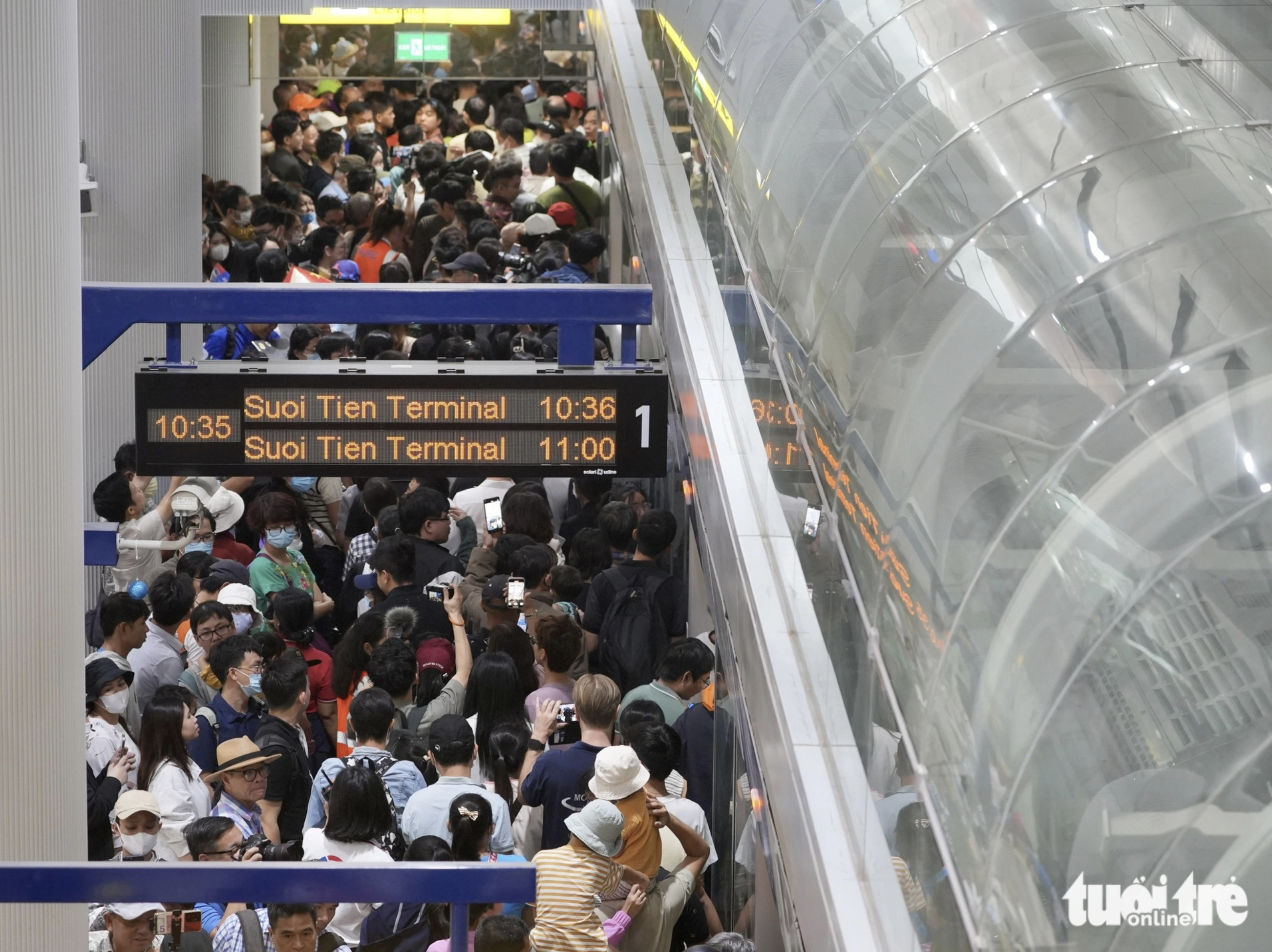 Residents stand in line and experience a long wait for boarding a metro train. Photo: Huu Hanh / Tuoi Tre