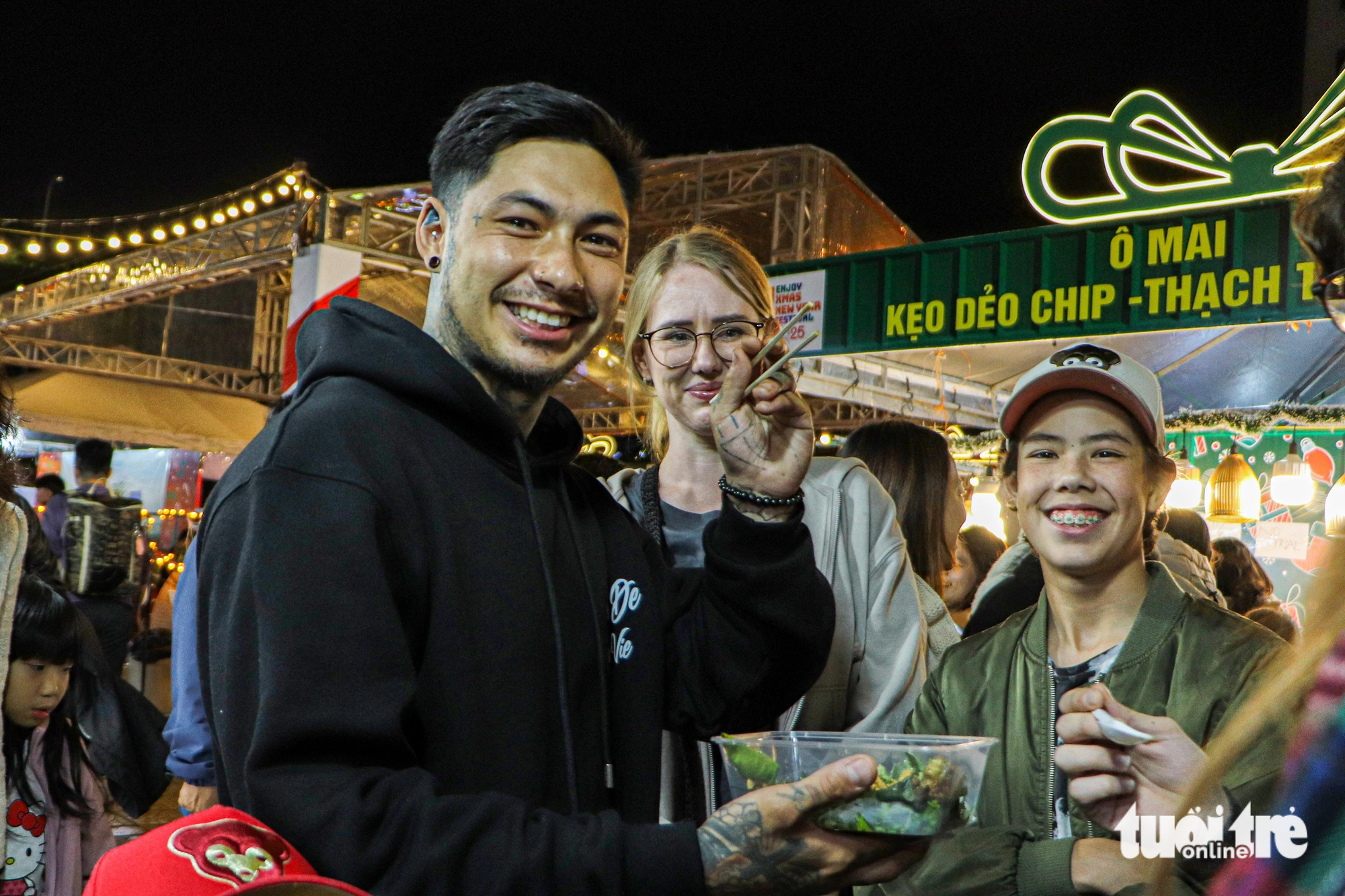 Foreign visitors try food at a Christmas bazaar on the bank of Dragon Bridge, Da Nang City, Central Vietnam. Photo: Thanh Nguyen / Tuoi Tre