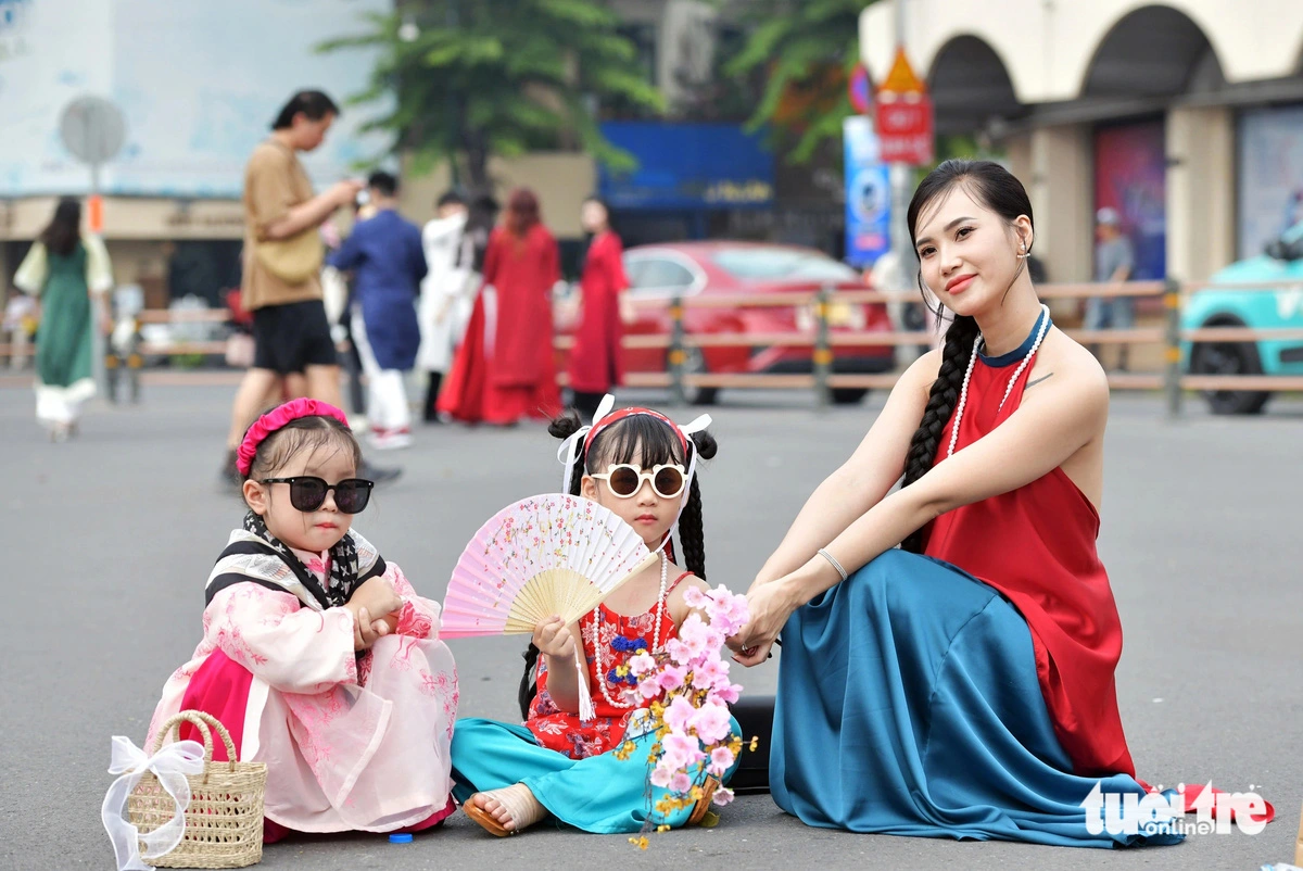 A young woman (R) and two children in Tet-themed outfits in Ho Chi Minh City.