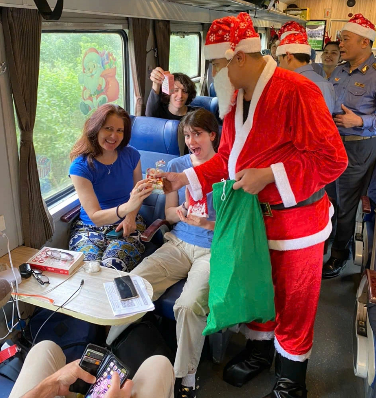 Passengers aboard a train are presented with a gift by a train attendant wearing a Santa Claus costume. Photo: Supplied