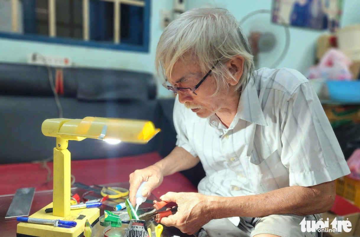 70-year-old Nguyen Tan Tien glues pieces of empty cans together to create a motorcycle. Photo: Ngoc Khai / Tuoi Tre