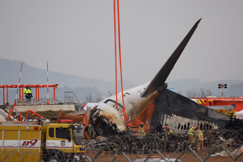 [7/11]People stand as the wreckage of an aircraft lying on the ground after it went off the runway and crashed at Muan International Airport is pictured, in Muan, South Korea, December 30, 2024. Photo: Reuters