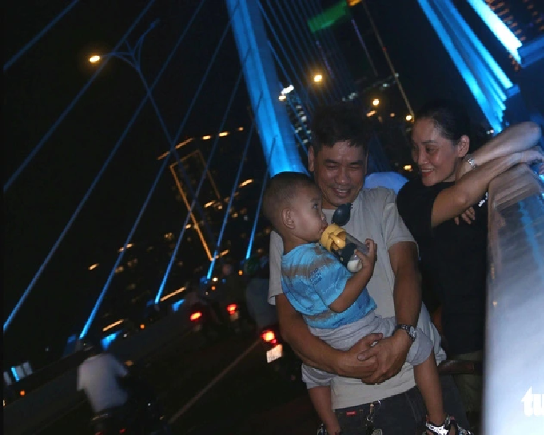 The family of Pham Ngoc Dung and Vu Thi Phuong admires the new look of the Ba Son Bridge in Ho Chi Minh City. Photo: Bui Nhi / Tuoi Tre