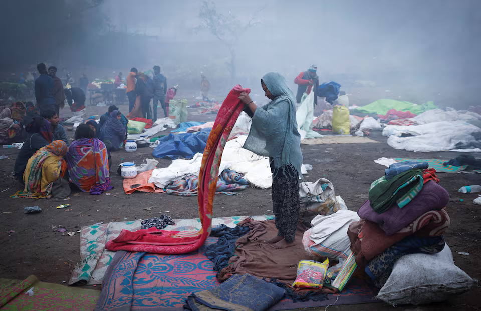 [3/5]A girl folds her blanket as others sit next to a fire at an open ground on a foggy winter morning in the old quarters of Delhi, India, January 3, 2025. Photo: Reuters